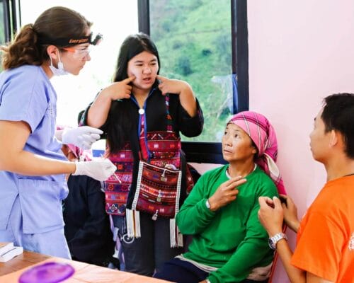 Photo of a volunteer interpreter asking questions of a patient to interpret for a doctor.